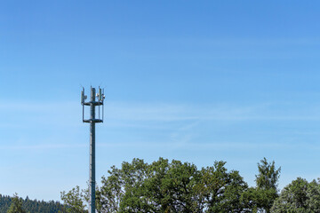 Telecom tower rises above green landscape under clear blue sky during daylight hours