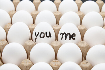 white chicken eggs in the cardboard egg tray with a words write YOU ME on it