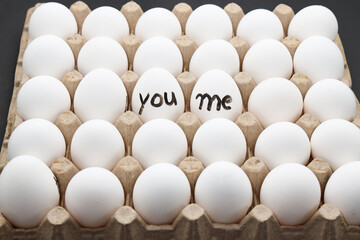 white chicken eggs in the cardboard egg tray with a words write YOU ME on it