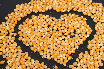 Yellow corn grains with a black background forming a heart drawing