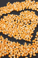 Yellow corn grains with a black background forming a heart drawing