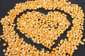 Yellow corn grains with a black background forming a heart drawing