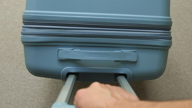 Traveler pulling telescopic handle of hard-shell luggage for trip