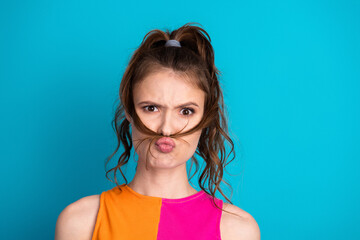 Expressive young woman with playful expression against vibrant blue background showcasing casual...