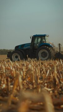 A tractor works diligently on a dusty field during the afternoon in the countryside, preparing the land for future crops. The sun casts a warm light on the hard-working machine