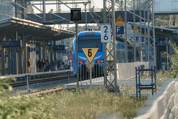 Train arrives at platform six in a bustling urban station during late afternoon