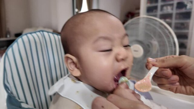A baby experiences a new taste for the first time, showcasing curiosity and excitement. The scene captures the delightful moment of feeding, highlighting the relationship between parent and child duri