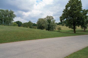 Obraz premium Scenic park landscape featuring rolling hills and lush greenery during a cloudy day