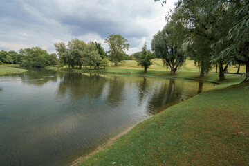 Serene lakeside view with lush greenery during cloudy afternoon at a peaceful park