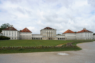 Naklejka premium Historic palace surrounded by serene gardens and cloudy skies in a tranquil setting in Munich, Germany