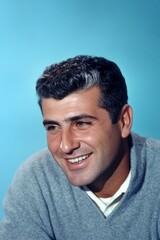 Obraz premium Blue solid background. A confident and modern man embracing his look. Fashionable men's soft perm haircut - midlife middle eastern man with short hair. Conceptual art of style for aging men.