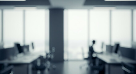 Blurred office interior with desks chairs and large windows a person working