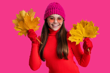 Teen girl with fallen leaves isolated on pink. Autumn girl hold fallen leaves. Fall and autumn. Autumnal season. Fall fashion. Happy young girl playfully hold yellow maple leaves. Golden leaves
