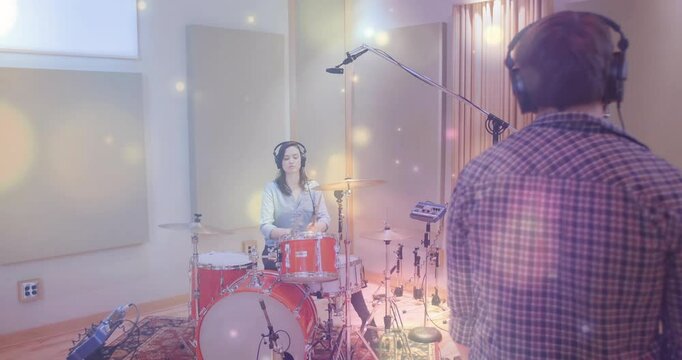 Female drummer tapping snare on red drum kit after engineer gesturing to start studio recording