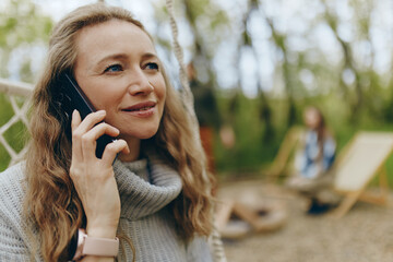 happy middle age woman talking on phone outdoors, promoting healthy wellbeing and active lifestyle