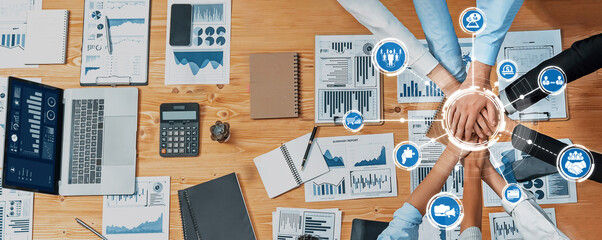 A dynamic overhead view of a collaborative business meeting featuring hands in unity, charts, and...