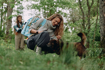 Fototapeta premium Active middle age woman enjoying time outdoors with her dog in lush green forest, promoting healthy lifestyle, wellbeing, and fitness for older women.