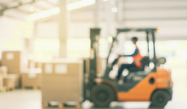 Person operating a forklift in a warehouse with cardboard boxes blurred.