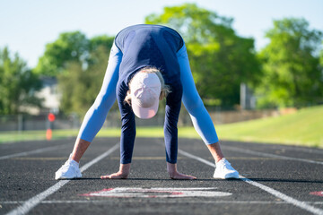 Woman doing stretching exercises on track-and-field course 
