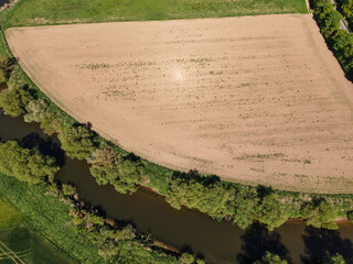 A breathtaking aerial view showcases an agricultural field right next to a serene stream Koldinger...