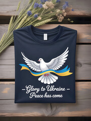the end of the Russia-Ukraine war, featuring a navy t-shirt with a white dove holding a Ukrainian ribbon and the inscription "Glory to Ukraine - Peace has come," alongside dried flowers