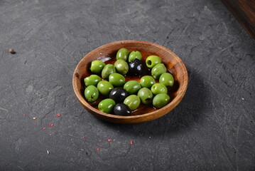 Green olives and black olives in a denim plate on a gray background