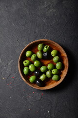 Green olives and black olives in a denim plate on a gray background