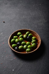Green olives and black olives in a denim plate on a gray background