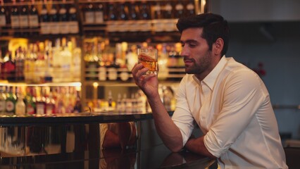 Smart man in white shirt drinking cocktail Old fashioned of special party beverage vibrant waiting for friends or couple at nightclub on Friday meeting night time at luxurious counter bar. Vinosity.