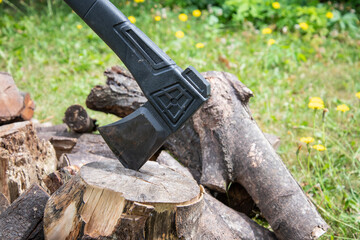 Outdoor scene with an axe embedded in a chopping block beside a pile of logs, suggesting rustic...