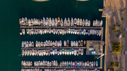 Drone top-down view of many boats and yachts moored in the Port of Marseille, France, showing clear water, docks, and marina layout.