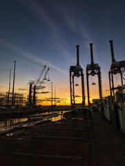 Grúas portuarias al atardecer con reflejos en zona industrial