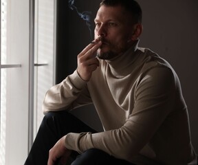 Man smoking cigarette near window in room