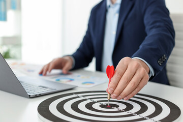 Man with dart aiming at dartboard while working indoors, closeup
