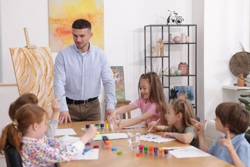 Fototapeta premium Man teaching kids to draw at painting lesson indoors