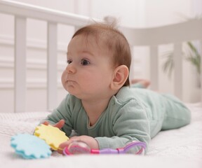 Cute little baby with rattle toy in crib at home