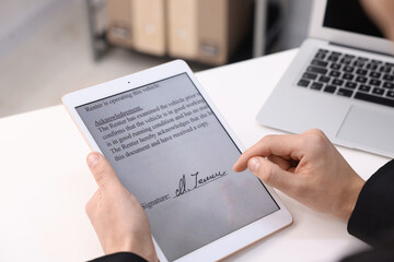 Electronic signature. Man using tablet at white table, closeup
