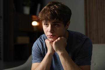 Teen problems. Upset teenage boy on sofa at home