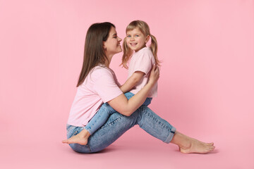 Happy mother and her cute daughter on pink background