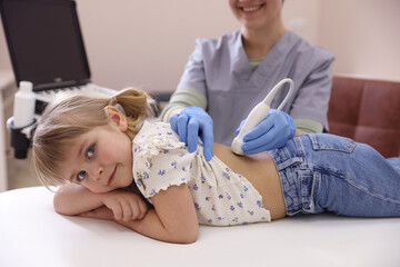 Sonographer conducting little girl's renal ultrasound examination in clinic, closeup