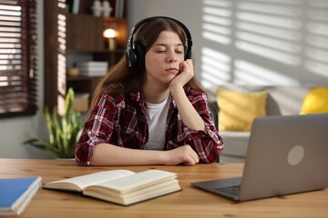 Stressed teenage girl studying at desk indoors