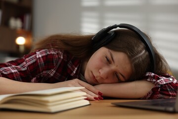 Stressed teenage girl studying at desk indoors
