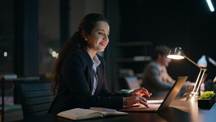Night managers looking each other typing keyboard laptop at coworking closeup