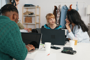 young adult woman and colleagues socializing and working together in a modern workplace, discussing...