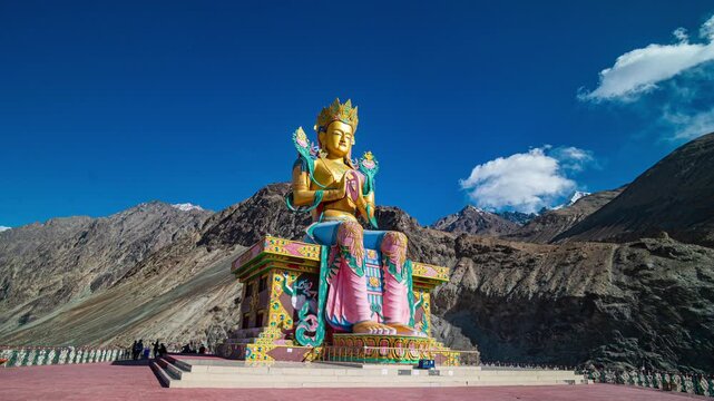 A breathtaking wide-angle view of Diskit Monastery crowned by the towering Maitreya Buddha statue, nestled in the dramatic Nubra Valley with the Himalayas forming a majestic backdrop