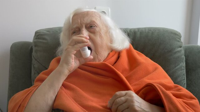 Senior woman inhales medicine for asthma