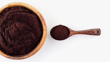 A wooden bowl and a spoon, both filled with brown powder, are placed on a light monochrome background. It can be cocoa or cinnamon, creating a natural and cozy look for culinary projects.