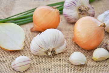 Garlic, yellow onion and green feathers. Vitamins on the table.