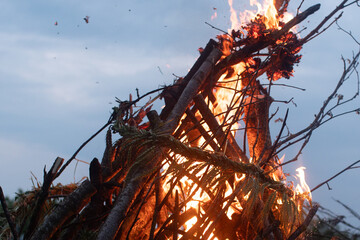 A large wood fire burns intensely at dusk, and a decorative wreath made of woven grain is visibly...