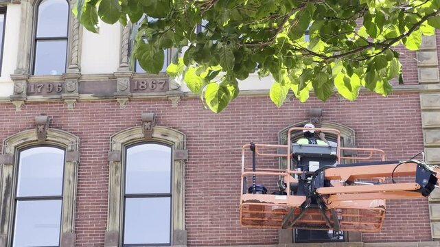 Elevated Window Trim Maintenance Worker In Caged Lift
